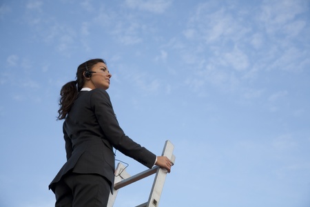 Young latin looking telephone operator  up on a ladder, with headphones.の写真素材