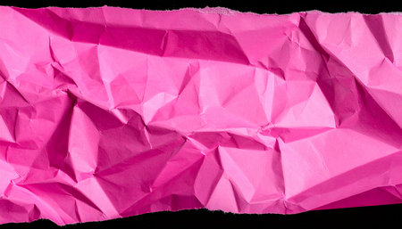 Pink crumpled paper isolated on black background with clipping path.の素材