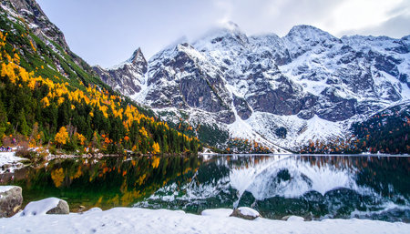 Landscape view of autumnal alpine lake and snow covered mountainsの素材
