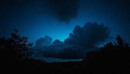 Night sky with clouds and silhouettes of trees in the foreground.の素材