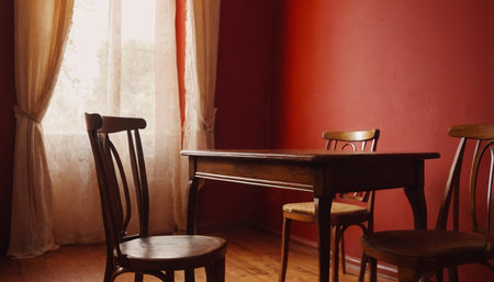 Vintage chairs and table in a room with red wall and windowの素材