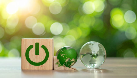 Green power button on wooden block with globe and green bokeh backgroundの素材