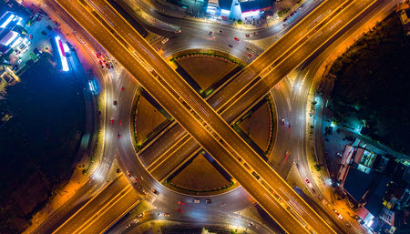 Aerial view of highway crossroads and roads in city at nightの素材