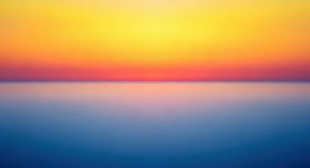 A minimalist and abstract depiction of a sunset with a smooth gradient of yellow, orange, and pink in the sky, reflected on calm, blurred blue water. Clear details and vibrant colors enhance vis...の写真素材