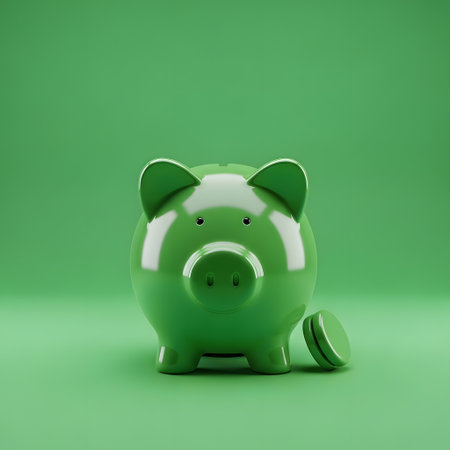 A shiny green ceramic piggy bank sits on a matching green surface, with a single coin resting beside it.の素材