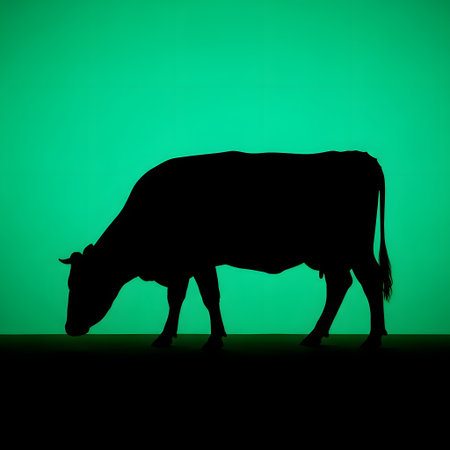 A dark silhouette of a cow is depicted with its head down, grazing in a field against a striking bright green sky.の素材