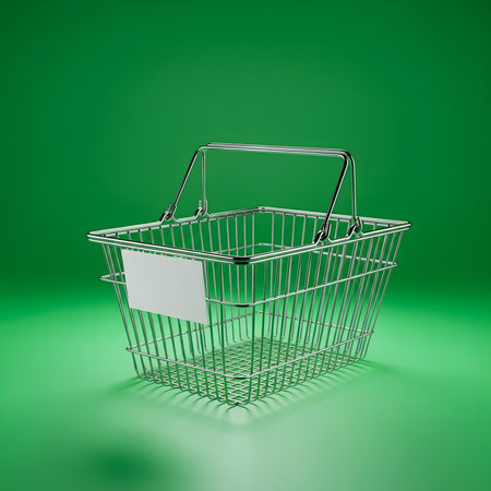 A small, shiny metal shopping basket with a white label sits on a vibrant green surface, casting a subtle shadow.の素材