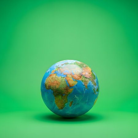 A detailed globe showcasing continents and oceans sits centered on a plain, bright green surface, casting a subtle shadow.の素材