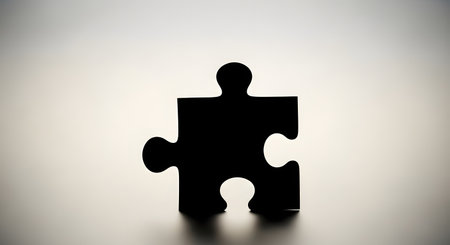 A solitary black puzzle piece is silhouetted against a softly lit, neutral background, casting a subtle shadow.の素材
