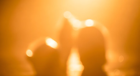 Two indistinct figures are illuminated by a soft, warm golden light, creating a dreamy and abstract atmosphere.の素材