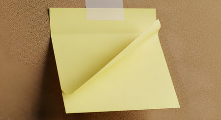 A close-up shot of a yellow sticky note partially peeling off a textured brown cardboard surface, secured with a strip of clear tape.の素材