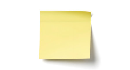 A blank, pale yellow sticky note is shown from a slightly angled perspective, casting a subtle shadow on a plain white surface.の素材