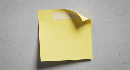 A single yellow sticky note is attached to a textured gray background, with its top corner peeling upwards.の素材