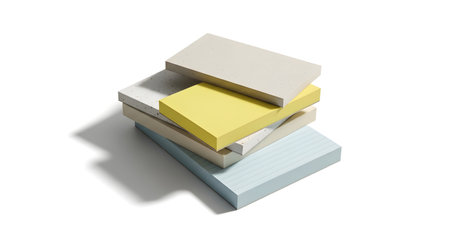 A high-angle shot of a small stack of pastel colored sticky note pads, casting a subtle shadow on a white surface.の素材