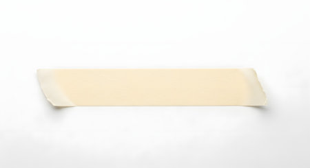 A rectangular piece of light beige masking tape is positioned horizontally against a plain white backdrop. The tape appears to be slightly angled.の素材