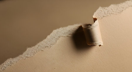 A textured surface with peeling paint and wallpaper revealing underlying layers. The light casts shadows, highlighting the rough edges and imperfections.の素材