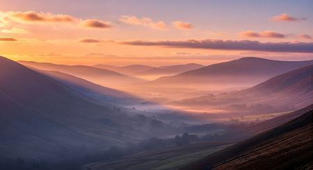 A breathtaking sunrise illuminates a misty mountain valley, casting a warm golden glow on the clouds and peaks.の素材