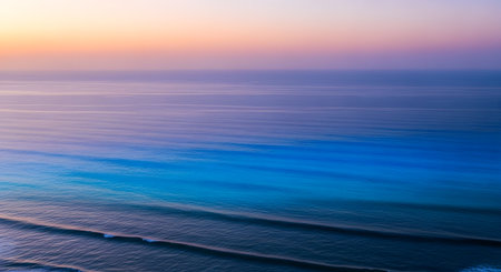 Calm ocean water reflects the gentle hues of a pastel sunset, creating a peaceful and tranquil seascape.の素材