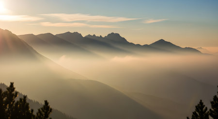 Jagged mountain peaks emerge from a thick layer of fog as the sun rises, casting a warm golden glow.の素材