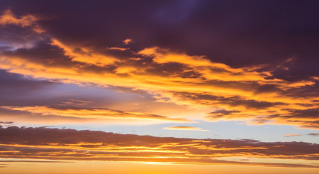 A breathtaking sunset paints the sky with dramatic streaks of fiery orange, yellow, and deep purple clouds.の素材