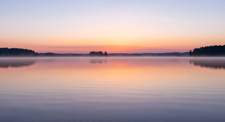 A tranquil lake at sunrise, reflecting pastel colors and gentle mist rising from the water's surface.の素材