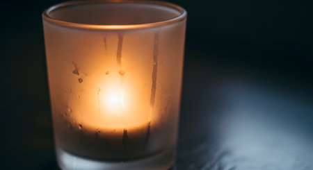 A single candle burns brightly within a frosted glass lantern, casting a warm, inviting light.の素材