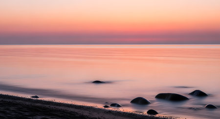 A tranquil ocean scene at dusk, featuring a gradient of pastel colors in the sky and gentle waves lapping against a rocky shore.の素材
