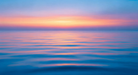 A tranquil ocean horizon at sunset, bathed in soft pastel colors of pink, orange, and blue, with gentle ripples on the water's surface.の素材