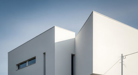 A minimalist architectural shot featuring stark white geometric forms and sharp angles set against a clear blue sky.の素材