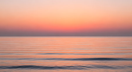 A tranquil ocean scene at sunset, featuring soft pastel colors in the sky and gentle waves lapping the shore.の素材