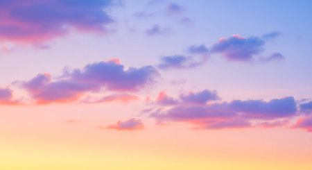 A serene sky painted with soft hues of pink, purple, and yellow, dotted with fluffy clouds.の素材