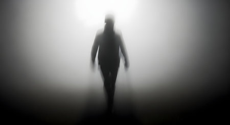 A shadowy, indistinct human silhouette stands in a bright, hazy light, creating a mysterious and haunting atmosphere.の素材