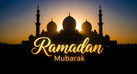 A mosque with minarets is silhouetted against a vibrant sunset sky, with 'Ramadan Mubarak' text.の素材