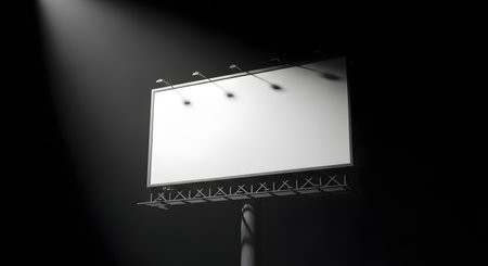 A blank billboard stands in the dark, brightly lit by a single, dramatic spotlight from above, ready for advertisement.の素材
