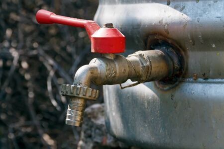 outdoor faucet mounted on metal water barrelの写真素材