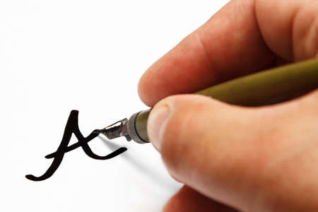 old neglected, rusted nib pen, with remnants of dried ink and man's hand write letter A on white...