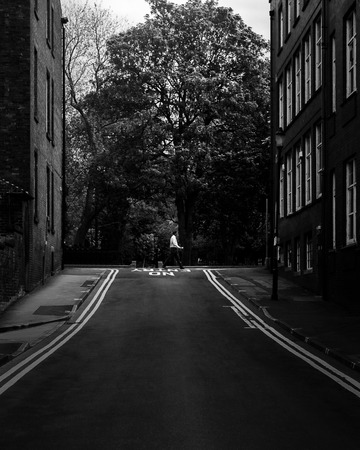 A man crosses the road ahead in the distance at the end of a city street in Prestonの写真素材