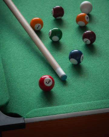A child's miniature pool table with numbered balls and a cue