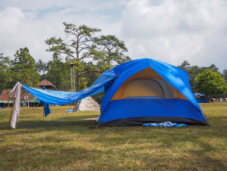 blue camping tent on the grass with cloudy sky