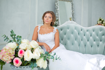 Beautiful, gentle bride in white wedding dress in luxury bright roomの写真素材
