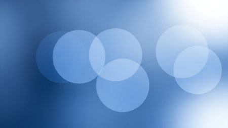 Abstract background featuring soft, out-of-focus blue circles of light, or bokeh, with a bright, hazy glow on the right side.の素材