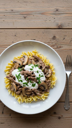 Appetizing dish of beef stroganoff with sautÃ©ed mushrooms, sour cream, and fresh parsley on a bed of egg noodles, served on a white plateの素材
