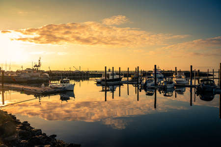 Beautiful sunset with clouds over marina with boats in Bandon, Oregonの写真素材