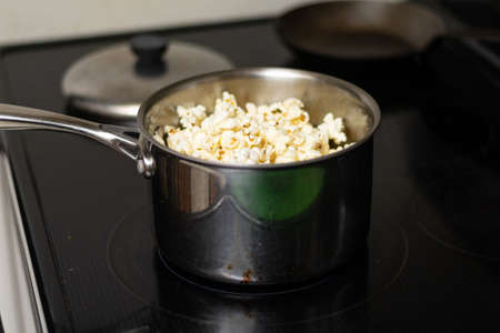 A pot sits on stove with fresh hot popcorn prepared at homeの写真素材