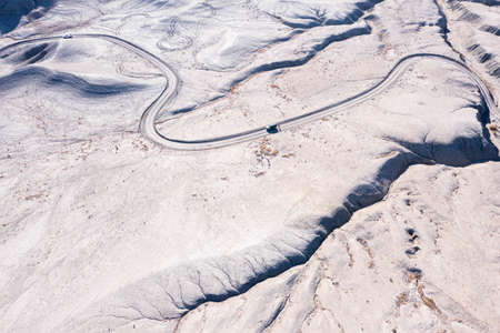 Off roading dirt road in Utah badlands. Vehicle and person on road.