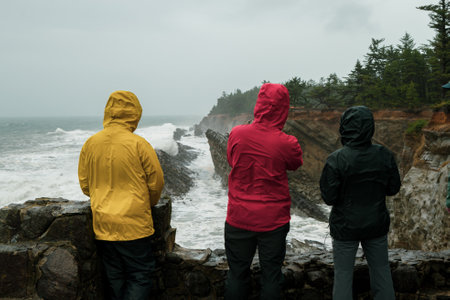 People in colorful outdoor clothing watch waves at the Oregon Coast.