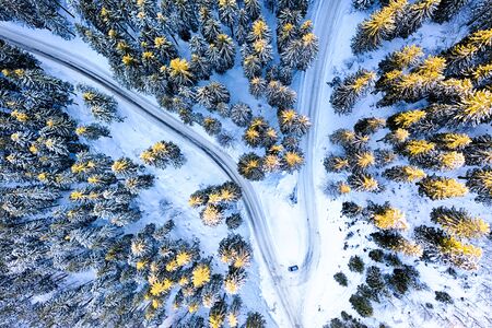 Car driving on a very icy road with snow. Aerial view to pine forest in the European Alps.の写真素材