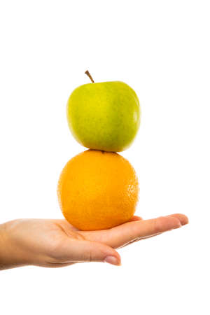Comparison of apples with oranges. Young female woman holding an apple and an orange in her hand.の写真素材