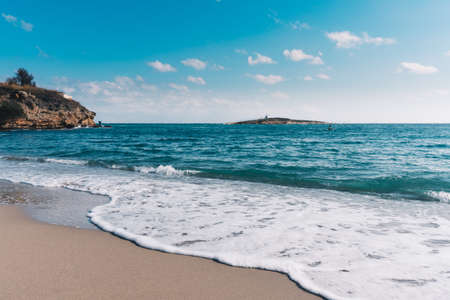 Beautiful blue Aegean See in Greece. View to the sand beach and water and a lonely idyllic small greek island.の写真素材