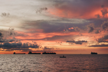 Dramatic Sunset Over the Adriatic Sea with Ships and Silhouetted Boat Near Koper, Sloveniaの写真素材